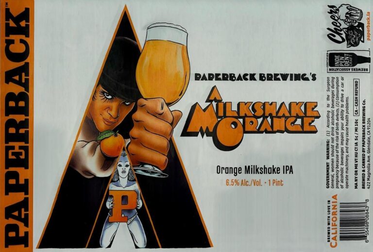 A Milkshake Orange beer label from Paperback: A figure in a black hat holds an orange fruit and raises a glass of amber liquid. A smaller superhero-like character stands below.