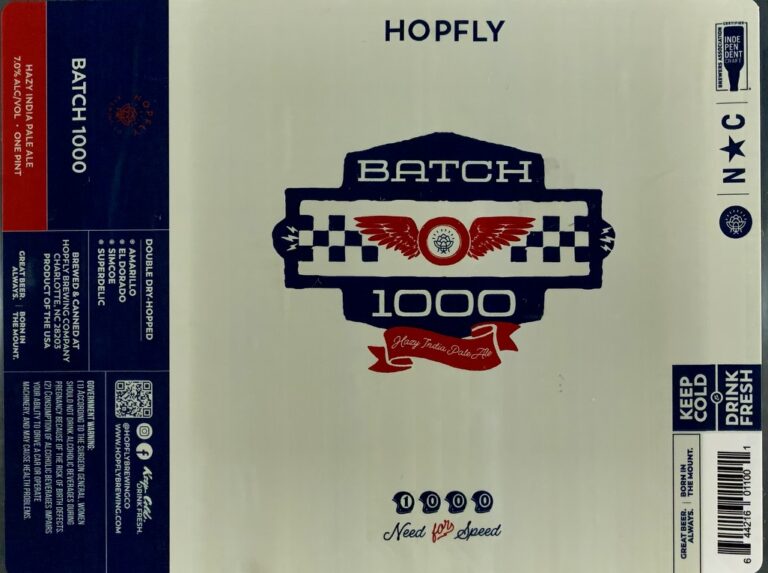 Batch 1000 beer label from Hopfly: A blue shield-shaped emblem with checkered borders and red wings flanking a central circular seal. Below it is a red ribbon banner reading 'Heavy India Pale Ale'.