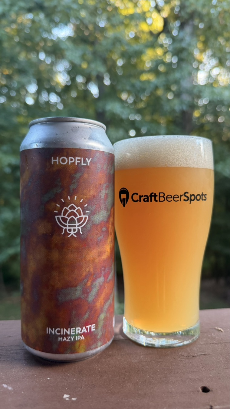 HopFly Incinerate can beside a hazy beer photographed by CraftBeerSpots